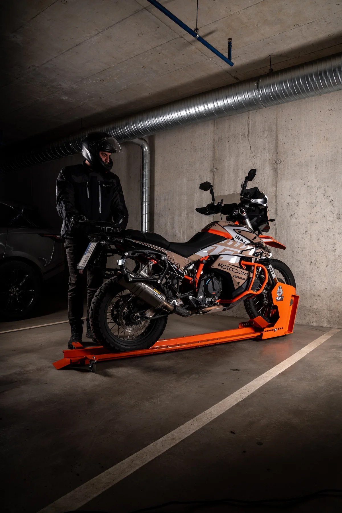 A motorcycle on a DockIT stand and a car sharing one underground parking space