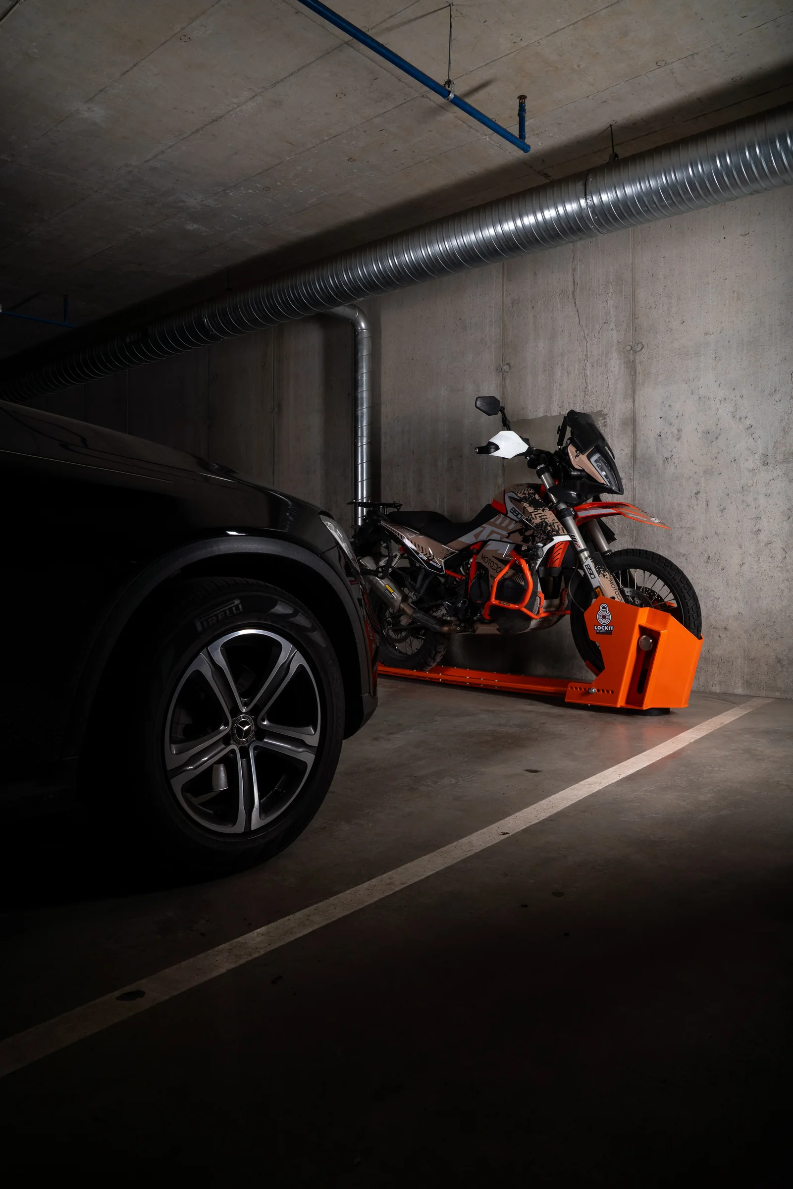 Motorcycle parked on a DockIT stand alongside a car within a single parking space