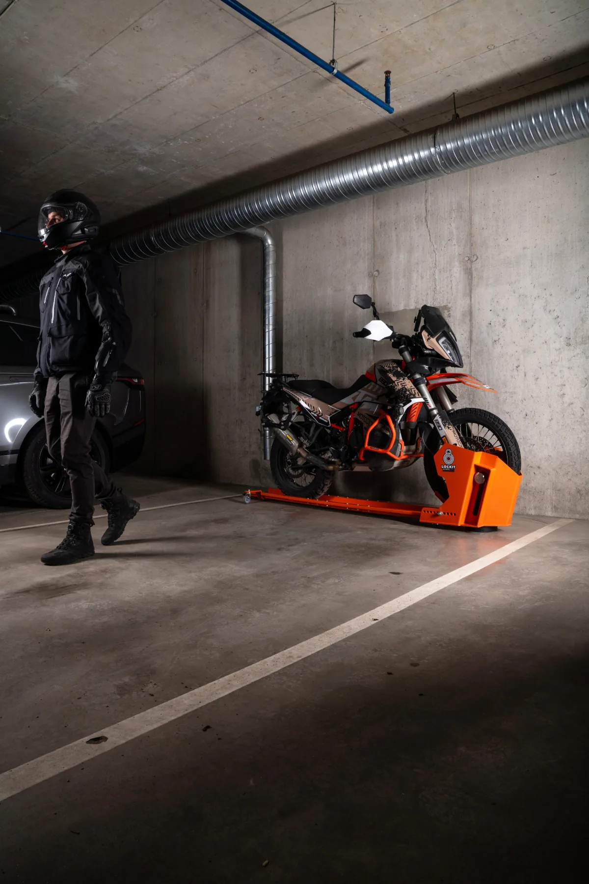 Motorcycle rotated parallel to the wall on a DockIT stand, the rider stepping away