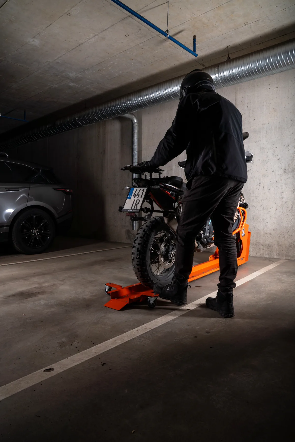 Rider riding a motorcycle into an orange DockIT stand in an underground car park