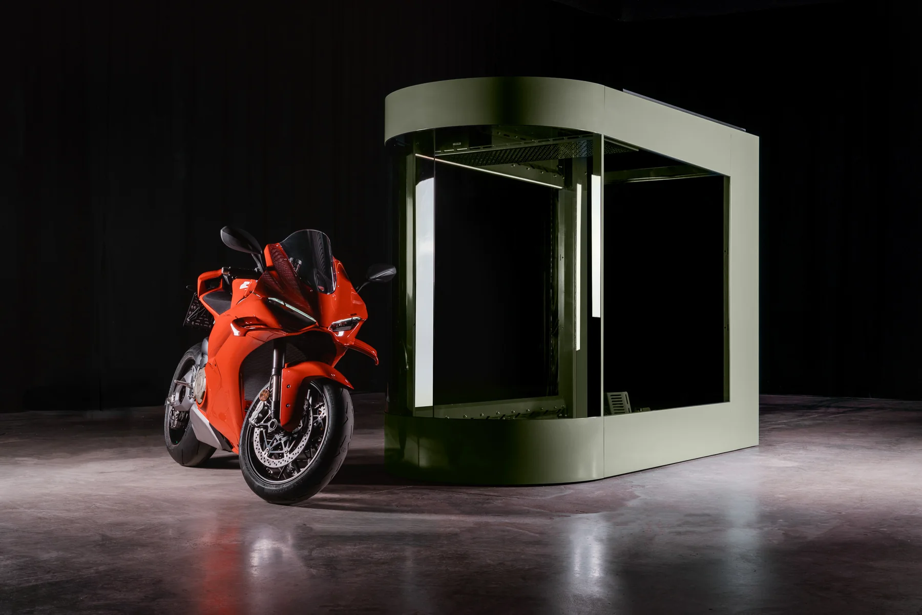 MotoDome motorcycle garage seen at an angle with its gate open and a red sportbike beside it