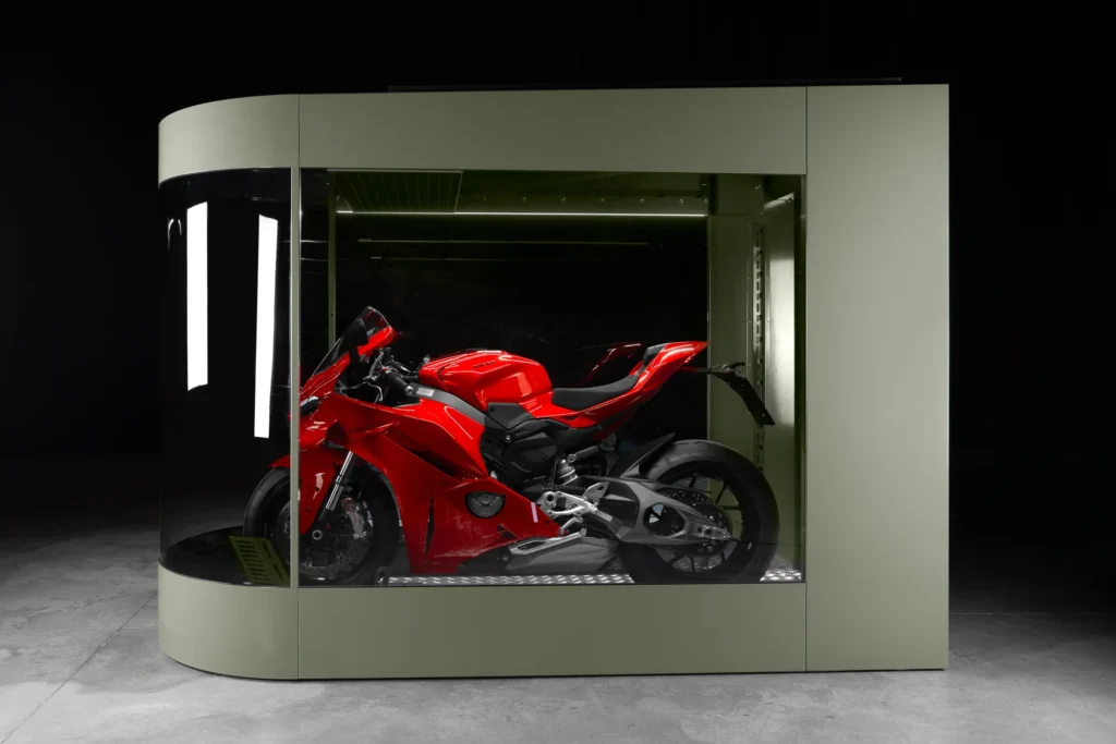 Red sportbike stored inside an olive MotoDome motorcycle garage with glass walls and LED lighting
