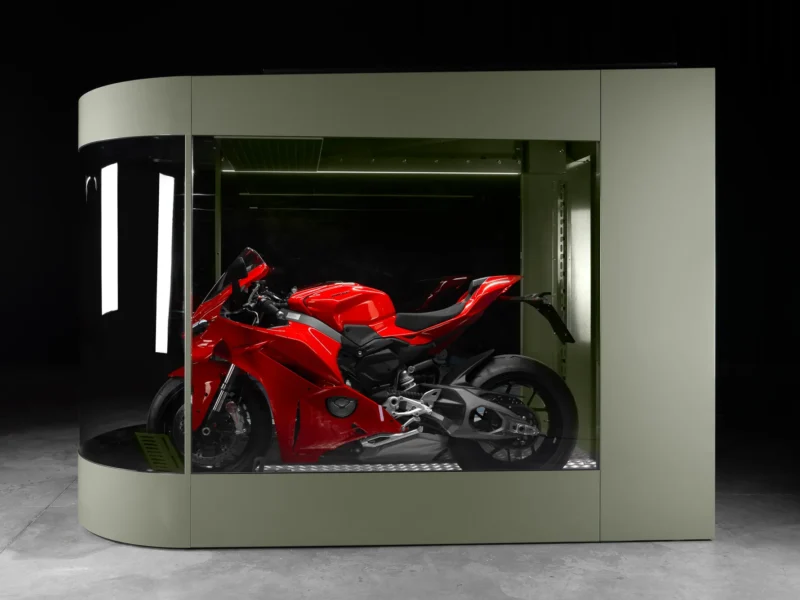 Red sportbike stored inside an olive MotoDome motorcycle garage with glass walls and LED lighting