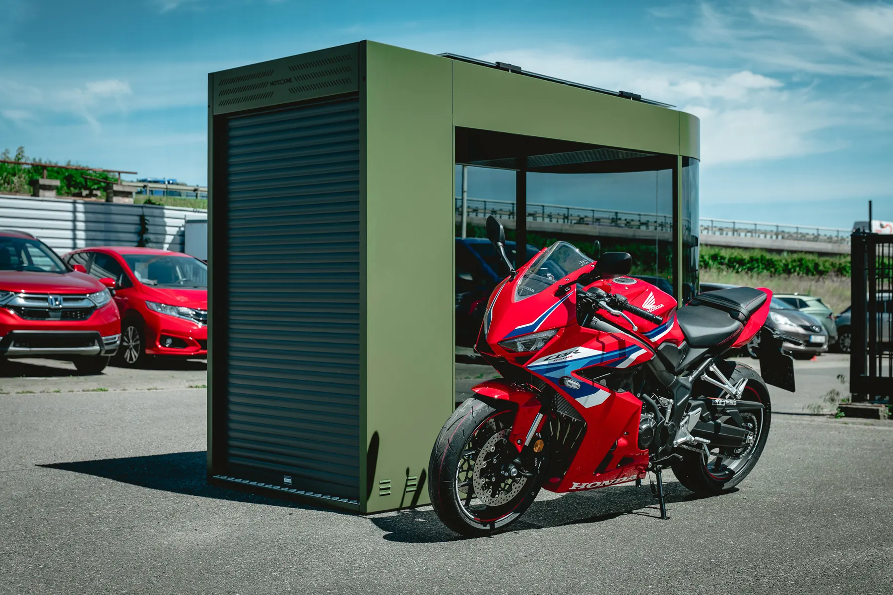 Olive green MotoDome motorcycle garage installed outdoors with a red sportbike
